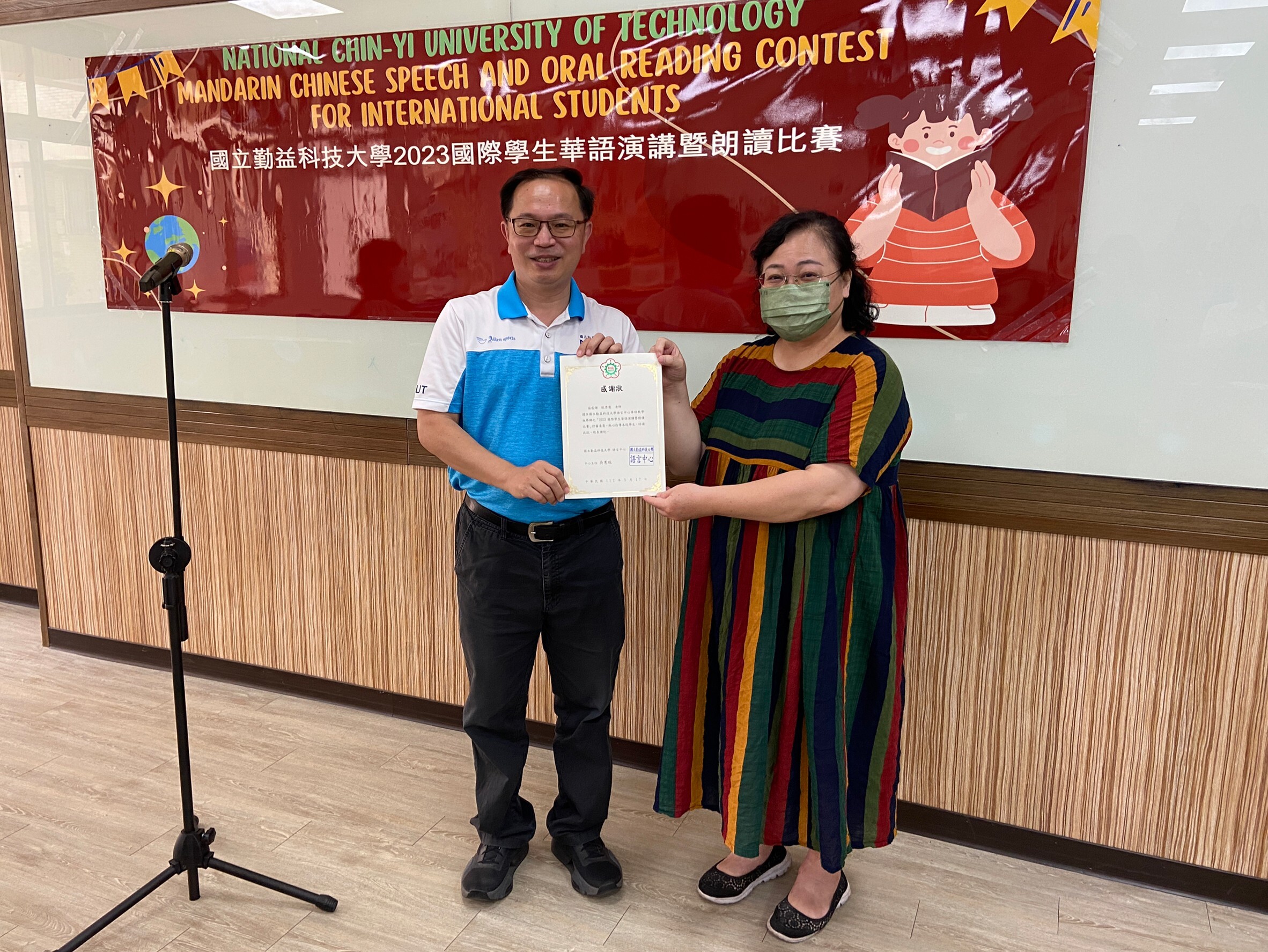 Another two people stand together with a cert document on their hand